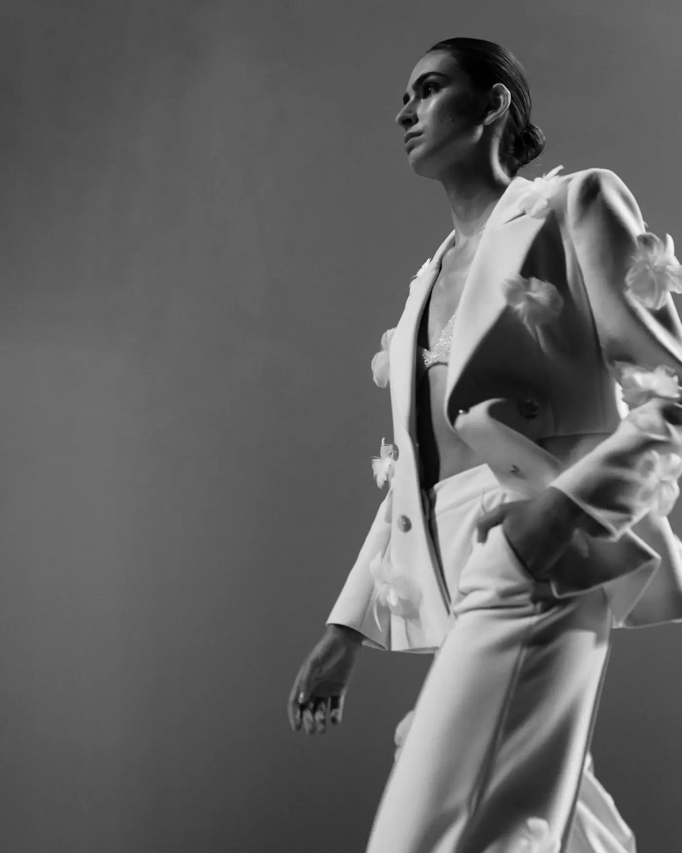 A model in a white tailored suit against a grey wall, in black and white