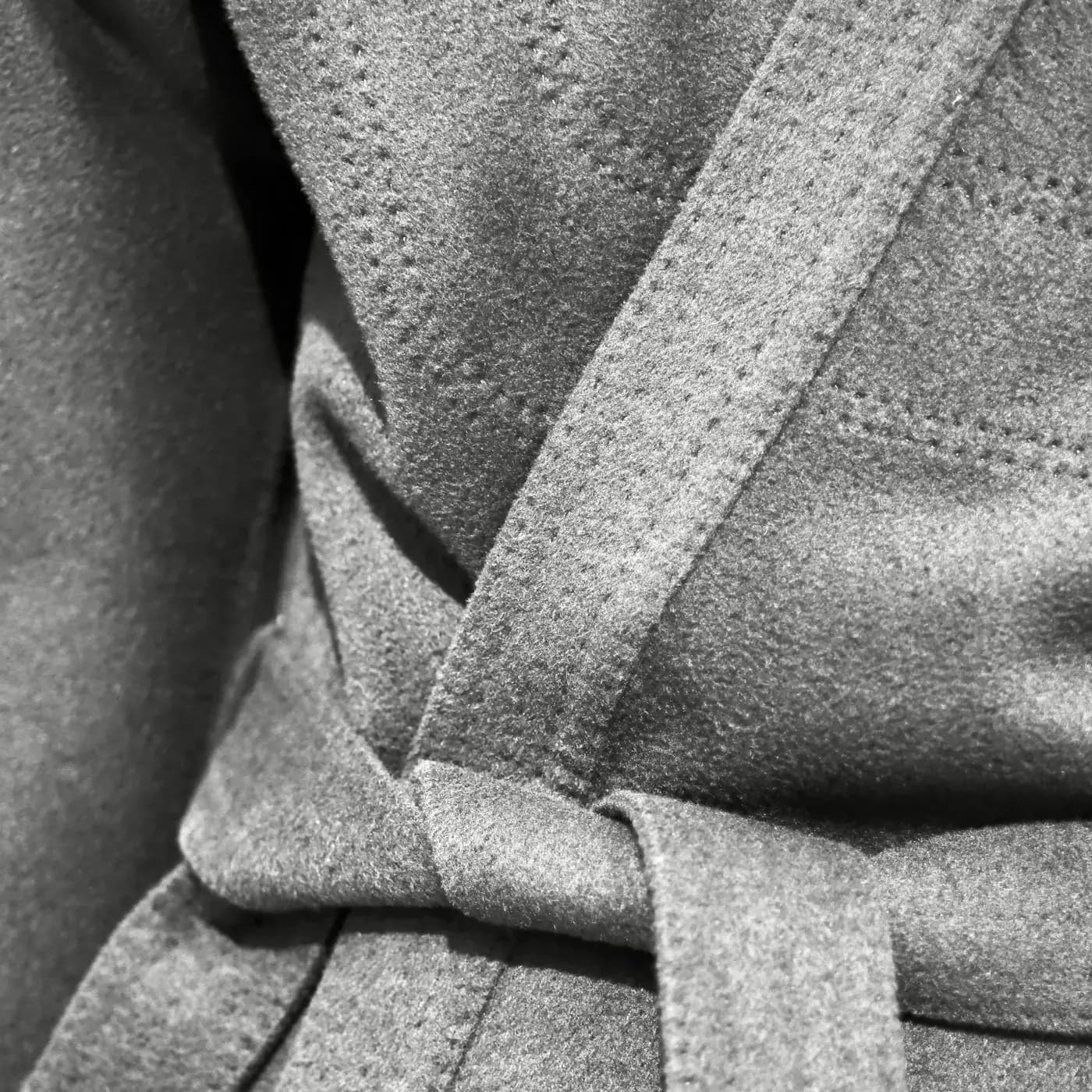 A grey wool belt knotted at the waist of a coat, close up